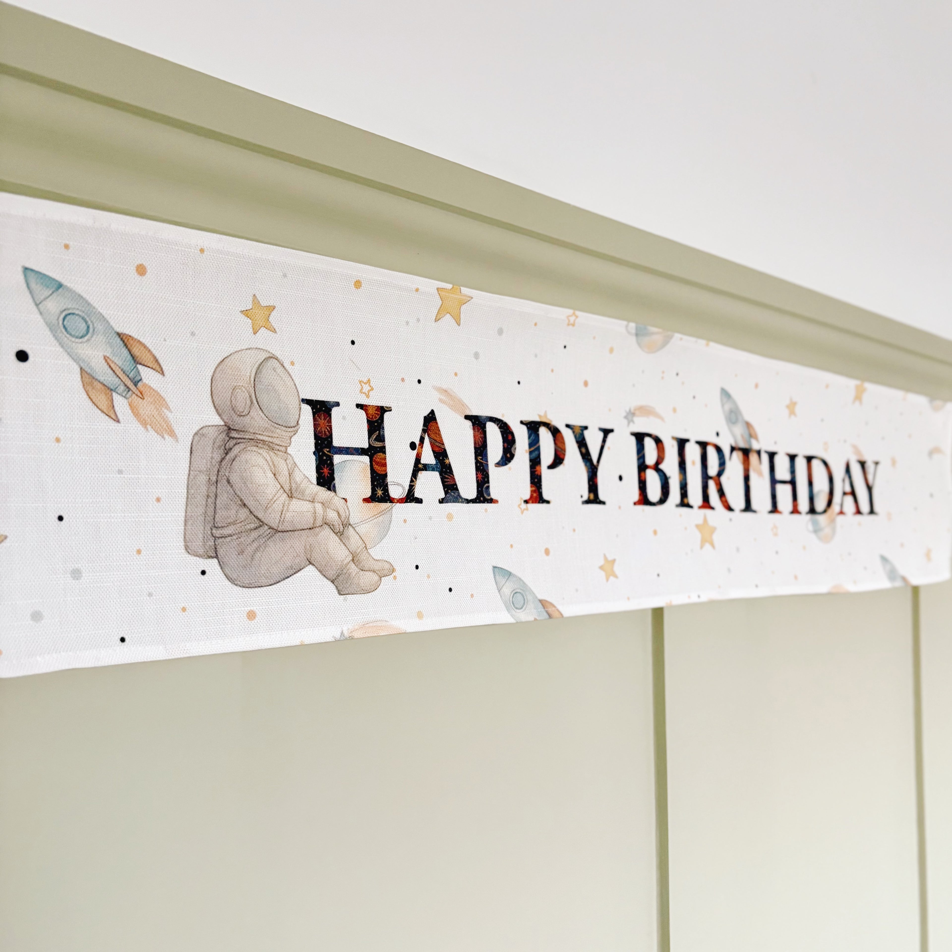 Space-themed 'Happy Birthday' banner with astronaut and rockets on a white background.